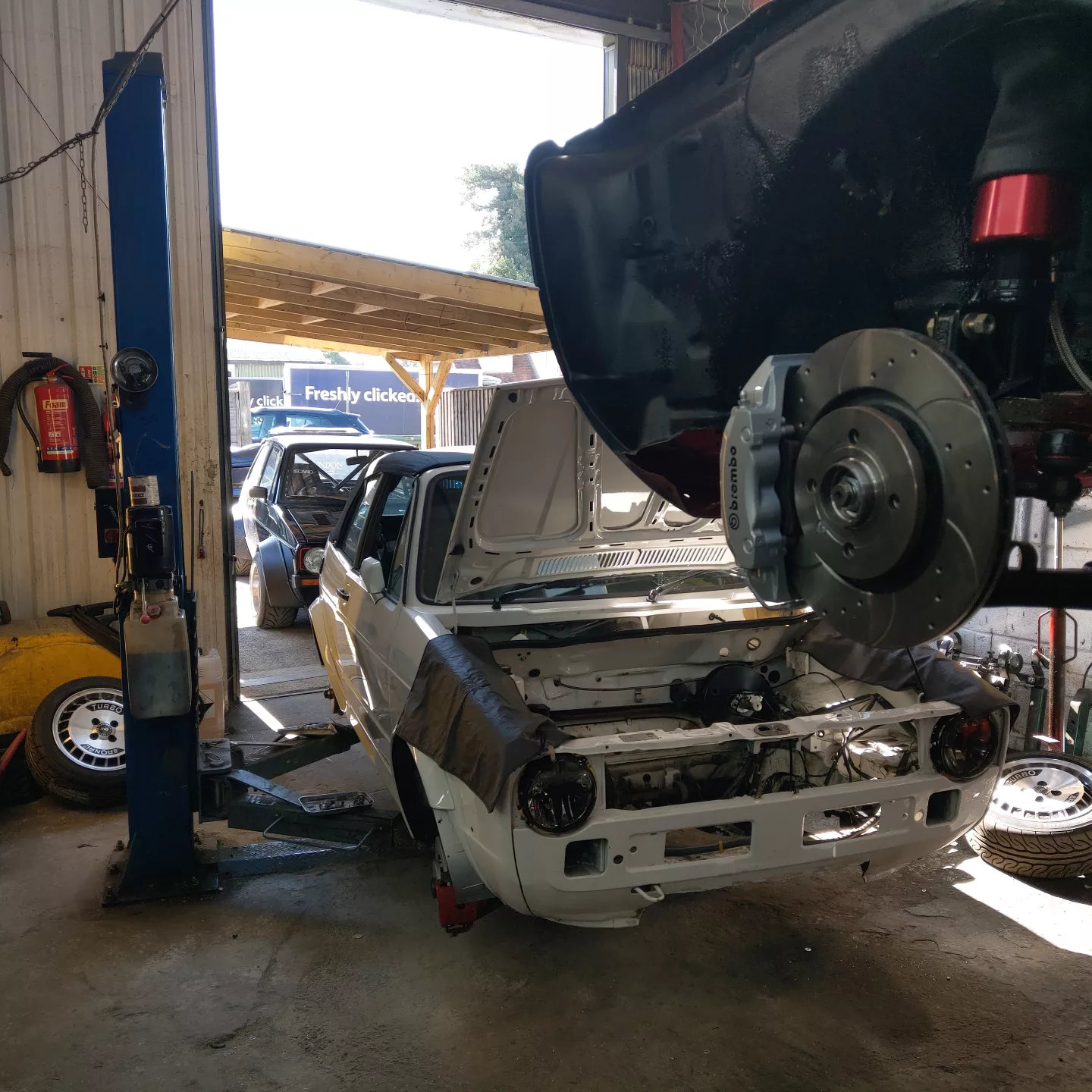 The workshop with a Mk1 on the two-post lift and a white Mk1 front end stripped below