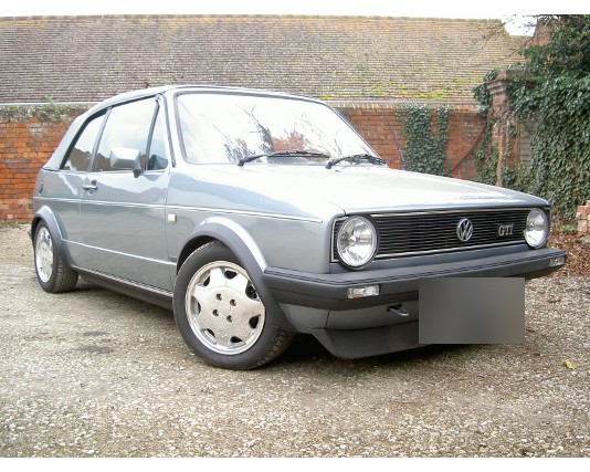 Silver Mk1 GTI parked on gravel by a brick wall