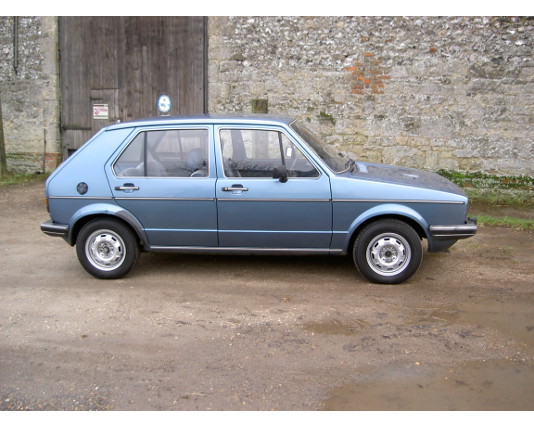 Blue Mk1 Golf five-door by a stone barn